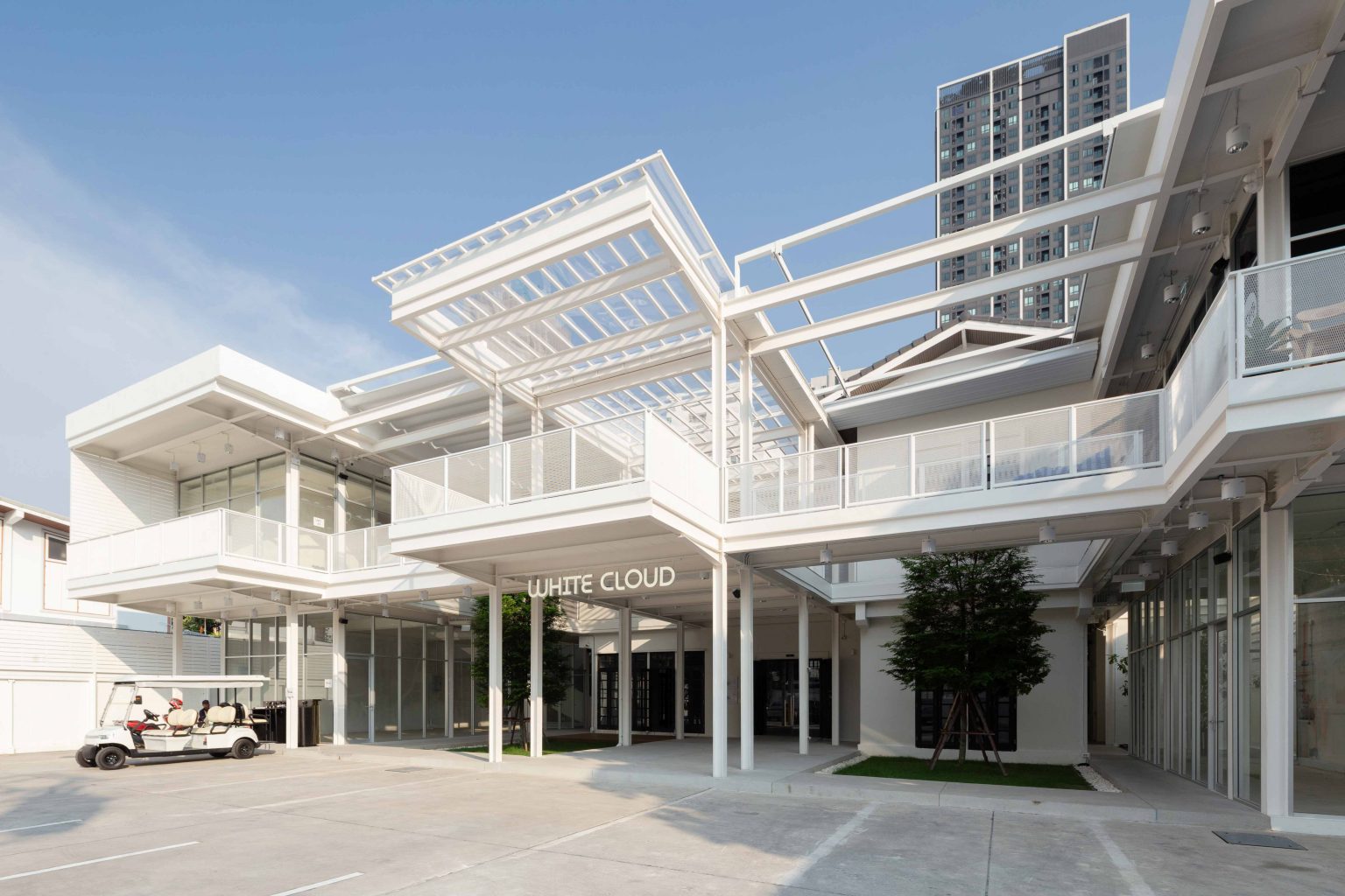 White Cloud Community Space – Community ฟีลบ้านเพื่อน ในพื้นที่บ้านเก่าอนุรักษ์และโครงสร้างใหม่จากเหล็ก SYS White Cloud Community Space เป็นการออกแบบพื้นที่ให้เช่าและ Community Space บนพื้นที่ย่านอารีย์ที่แต่เดิมมีบ้านหลังเก่าตั้งอยู่ โดยโจทย์ตั้งต้นคือการคงบ้านหลังเดิมที่มีความทรงจำและความสำคัญต่อเจ้าของที่ดินเอาไว้ สถาปนิกจึงทำการออกแบบพื้นที่ใช้งานใหม่โอบล้อมบ้านหลังเก่า เปลี่ยนบ้านเป็นไฮไลท์ และสร้างพื้นที่ใช้งานในร่มโอบล้อมโดยรอบ เพื่อให้ผู้คนเข้ามาใช้งานได้อย่างสะดวกสบายตลอดทั้งวัน ในพื้นที่อาคารประมาณ 1,200 ตารางเมตร (ไม่รวมพื้นที่จอดรถ) โครงการนี้ออกแบบโดย คุณอภิชัย จารุรัตนเกื้อ หรือคุณปริ้นท์ Architect Designer จาก Design to the Universe Co., Ltd. (บริษัท ดีไซน์ ทู เดอะ ยูนิเวิร์ส จำกัด) ผู้มีประสบการณ์ในการออกแบบงาน Commercial, Hospitality & Education Building ในหลากหลายโครงการ เช่น Holiday Pastry หน้าร้านชงดีที่ One Bangkok และ Central World หรือโรงพยาบาลหลายแห่ง เป็นผู้นำในการออกแบบ แบ่งสัดส่วนพื้นที่อย่างเป็นระบบ และสร้างเอกลักษณ์ให้กับแบรนด์ได้อย่างโดดเด่น ในโครงการ White Cloud Community Space ด้วยความต้องการให้ Space โปร่งโล่ง มีกรอบเวลาที่ชัดเจน และง่ายต่อการรื้อถอนหลังหมดสัญญาเช่า ทางสถาปนิกจึงเลือกใช้เหล็กโครงสร้าง H-BEAM จาก SYS เป็นโครงสร้างหลักของโครงการ เพราะมีคุณสมบัติที่ตอบโจทย์ทั้งงานดีไซน์ ความแข็งแรง และจัดการก่อสร้างได้สะดวก ส่งผลให้โครงการนี้เสร็จสิ้นได้รวดเร็ว มีดีไซน์ที่โปร่งโล่ง ไม่มีเสาโผล่กลางพื้นที่และตอบโจทย์เรื่องการรักษ์โลกได้จริง เป็น Community Space ยุคใหม่ ที่คุ้มค่าต่อเจ้าของโครงการในระยะยาว อีกทั้งยังสร้างความประทับใจ ความทรงจำ และประสบการณ์การใช้งานที่อบอุ่นและพิเศษให้กับผู้คนได้ทุกครั้งที่เข้ามาใช้งาน จากบ้านเก่าย่านอารีย์สู่ Community แห่งใหม่ในคอนเซ็ปต์ไข่แดง โครงการ White Cloud Community Space เริ่มต้นมาจากเจ้าของโครงการที่ต้องการเปลี่ยนบ้านเช่าหลังเก่าที่มีเอกลักษณ์เฉพาะตัวในย่านอารีย์ กรุงเทพมหานคร ให้กลายเป็น Commercial Building ที่ผู้คนสามารถเข้ามาใช้งานได้อย่างอิสระ ในขณะเดียวกันก็เปิดพื้นที่เช่าให้กับร้านค้าต่าง ๆ เข้ามาประกอบกิจกรรม ออกแบบโดยคุณอภิชัย จารุรัตนเกื้อ หรือคุณปริ้นท์ Architect Designer จาก Design to the Universe Co., Ltd. (บริษัท ดีไซน์ ทู เดอะ ยูนิเวิร์ส จำกัด) เดิมพื้นที่มีบ้านเก่า 2 ชั้นตั้งอยู่ และด้วยการเป็นพื้นที่เช่า เมื่อจบสัญญาเช่าเจ้าของโครงการจำเป็นต้องคืนพื้นที่ในสภาพเดิม ดังนั้นโครงการจึงเน้นไปที่การต่อเติมและสร้างโครงสร้างใหม่เข้ามาเสริม เพื่อรักษาโครงสร้างของบ้านเดิมเอาไว้ให้มากที่สุด และถือโอกาสชูบ้านหลังนี้ให้เป็นจุดเด่นของโครงการด้วย ทำให้บรรยากาศเสมือนการมานั่งเล่นที่บ้านเพื่อน เมื่อต้องการรักษาโครงสร้างเดิมของตัวบ้านเอาไว้ สถาปนิกจึงใช้การออกแบบและวางโครงสร้างส่วนใหม่เข้าไปรอบบ้านแทน เปรียบเสมือน “ไข่แดง (ตัวบ้านเดิม)” ที่ถูกล้อมรอบด้วย “ไข่ขาว (โครงสร้างใหม่)” โดยมีการวางพื้นที่จอดรถไว้ด้านหน้า ช่วยสร้างระยะการรับรู้จากถนน ให้ผู้ใช้งานสามารถมองเห็นความสวยงามของสถาปัตยกรรมและสัมผัสได้ถึงบรรยากาศสบาย ๆ ของโครงการได้ตั้งแต่ทางเข้า ส่วนตัวบ้านเดิมจะเป็นกระบวนการแบบ “กึ่งอนุรักษ์” คือพยายามรักษาวัสดุ โครงสร้างเดิมเอาไว้ เพื่อให้ความทรงจำของบ้านเด่นชัดและสื่อสารความรู้สึกแก่ผู้เข้ามาใช้งานได้อย่างชัดเจนที่สุด นอกจากนี้ยังใช้ “สวน” เพื่อแบ่งโซนการใช้งาน คือ สวนหน้าบ้าน เพิ่มความเขียวให้โครงการดูร่มรื่น และสวนหลังบ้านที่เป็นไฮไลท์ของโครงการ ที่มีร้านค้าหลากหลาย รวมถึงที่นั่ง บริเวณนี้จึงเกิดกิจกรรมและการเคลื่อนไหวค่อนข้างมาก เสริมให้โครงการมีชีวิตชีวามากขึ้น โครงการสีขาว เบาสบาย กับโจทย์ตั้งต้นที่โครงสร้างเหล็กกลายมาเป็นคำตอบ จากโจทย์หลักที่เป็นพื้นที่เช่า “โครงสร้างเหล็ก” จึงกลายเป็นคำตอบที่ชัดเจนสำหรับการออกแบบ เพราะโครงสร้างเหล็กสามารถต่อเติมได้สะดวกและรวดเร็วในพื้นที่ทุกขนาด เช่นเดียวกับโครงการนี้ที่ถนนหน้าโครงการค่อนข้างแคบ การเลือกความยาวเหล็กสำเร็จมาจากโรงงานทำให้การขนส่งเข้ามายังหน้างานเป็นไปอย่างราบรื่น อีกทั้งเหล็กยังสามารถติดตั้งได้รวดเร็ว ไม่กระทบโครงสร้างบ้านหลัก ตลอดจนไม่ก่อมลภาวะทางเสียงหรือฝุ่นให้กับบริบทข้างเคียงที่เป็นย่านที่พักอาศัย โดย White Cloud Community Space ใช้เวลาในการจัดการโครงสร้างเหล็กประมาณ 6 เดือนเท่านั้น (หากรวมระยะเวลาออกแบบจะใช้เวลา 9 เดือน) คุณปรินท์เล่าถึงความสำคัญของ “เวลา” ในโครงการประเภท Commercial Building ว่าโครงการประเภทนี้มักจะมีระยะเวลาในการเกิดชัดเจน ดังนั้นจึงเป็นเรื่องสำคัญมากในการเลือกใช้วัสดุให้เหมาะกับแบบที่คิดไว้และระยะเวลาที่มี ซึ่งเหล็ก H-BEAM จาก SYS ก็ตอบโจทย์ทั้งเรื่องระยะเวลาและรองรับรูปแบบของดีไซน์ที่ต้องการได้เป็นอย่างดี ไม่ว่าจะเป็นความโปร่ง เบา บางของโครงสร้าง เพื่อให้อาคารดูทันสมัย เท่เรียบง่าย แต่ไม่บดบังตัวตนของบ้านเดิม Span (ระยะห่างระหว่างเสา) ที่ยืดได้ยาวขึ้น เป็นอีกหนึ่งข้อดีของการเลือกใช้เหล็กเช่นกัน เมื่อเทียบกับโครงสร้างคอนกรีตที่ต้องมีการหล่อโครงสร้างเสาคาน อาจต้องมีคานทุก 4 เมตร ทำให้หนัาตัดคานอยู่ที่ประมาณ 40 – 50 เซนติเมตร (รวมความหนาคอนกรีตที่เททับด้านบนพื้น) แต่เมื่อเป็นโครงสร้างเหล็ก สามารถยืด Span ได้กว้างกว่าเดิม อีกทั้งในโครงการยังเลือกใช้โครงสร้าง Steel Truss ทำให้ยืดได้กว้างขึ้น ใช้จำนวนเสาในการรับน้ำหนักน้อยลง ส่งผลให้พื้นที่มีความโปร่งโล่งได้อย่างที่ต้องการ Highlight โถงสูงกลางบ้าน สร้างพื้นที่ให้กิจกรรมเชื่อมโยงถึงกัน สถาปนิกมองเผื่อไปยังอนาคตว่า ณ Community Space แห่งนี้อาจมีการขยายตัวของกิจกรรม เช่น การจัดคอนเสิร์ต จัดงานอีเวนต์ หรือทำการแสดงต่าง ๆ ซึ่งจะมีการรวมตัวของผู้คนจำนวนมาก ดังนั้นจึงเป็นแนวคิดที่ดีหากในโครงการมีพื้นที่โถงกลางเพื่อรองรับกิจกรรมนั้น โดยเมื่อเดินเข้ามาด้านในอาคาร จะเจอกับโถง Double Space ที่ฝ้าสูงประมาณ 7 – 8 เมตร มีพื้นที่ลานขนาดใหญ่ และมีการออกแบบเป็นอัฒจรรย์หรือ Amphitheater สีขาวขนาดใหญ่ที่สามารถใช้เป็นทั้งบันไดเชื่อมต่อไปยังชั้น 2 ของอาคารและใช้เป็นที่นั่งได้ ส่วนฝ้าเพดานออกแบบให้เป็นตารางรังผึ้ง มีการสลับกับช่องเปิดเพื่อนำแสงธรรมชาติลงมาสู่พื้นที่ผ่านหลังคาลอนคู่ใส 2 โทนสี คือ ลอนใสและลอนที่เคลือบสีเหลืองอบอุ่น ช่วยลดการเปิดไฟในตอนกลางวันและทำให้โถงสว่างเพียงพอต่อการใช้งาน อีกทั้งยังได้แสงที่นุ่มนวลและมีมิติมากขึ้น นอกจากนี้ยังมีการเติมรายละเอียดตามจุดต่าง ๆ ของอาคารเพื่อให้ภาพลักษณ์ สีสันที่ดูขาวสว่าง โปร่งโล่งนั้นเชื่อมโยงโดยทั่วกัน ผ่านดีไซน์ของขาโต๊ะที่ใช้เหล็ก H-BEAM นำมาตัดให้ได้ระยะใช้งานที่เหมาะสม หรือการเพิ่มฉากระแนงสีขาวแบ่งพื้นที่ใช้งานให้เป็นสัดส่วนแต่ยังคงเชื่อมโยงถึงกันผ่านการมองเห็น หลังคาที่ถูกยกความสูง เพิ่มความโปร่งให้ Space เหล็ก H-BEAM จาก SYS ไม่ได้ถูกใช้เป็นโครงสร้างของอาคารหลังใหม่เพียงเท่านั้น แต่ยังถูกใช้เพิ่มต่อเติมและเสริมให้บ้านเดิมมีความโปร่งโล่งแข็งแรงมากขึ้น ดีเทลหนึ่งที่น่าสนใจของโครงการ คือการใช้เหล็ก H-BEAM เข้ามายกความสูงของโครงสร้างหลังคาของบ้านเดิมขึ้น จากเดิมที่เพดานชั้นสองของบ้านค่อนข้างต่ำ เมื่อถูกรื้อฝ้าออกเพื่อโชว์ให้เห็น Slope ของโครงหลังคา ทำให้พื้นที่ภายในดูโปร่งมากขึ้น ส่วนของชั้นหนึ่งเองก็มีการยกเพดานขึ้นเช่นกัน โดยใช้โครงสร้างเหล็กต่อเข้ากับโครงสร้างคอนกรีตเดิมเพื่อพยุงโครงสร้างบ้านทั้งหมดให้มั่นคง อีกทั้งยังมีการรื้อฝ้าเพดานออกเพื่อให้พื้นที่ได้ความสูงโปร่งมากขึ้น โครงสร้างเหล็ก H-BEAM สีขาวที่ต่อเติมเข้ามามีความทันสมัยที่ตัดกับบรรยากาศบ้านโมเดิร์นที่ดูย้อนยุค ทำให้เกิด Contrast ของพื้นที่ที่น่าสนใจ เสมือนเดินเข้าสู่อาคารอนุรักษ์แบบร่วมสมัย เหล็ก = วัสดุที่ตอบโจทย์คุ้มค่าตั้งแต่วันแรกที่เลือกใช้ จนถึงวันสุดท้ายที่รื้อถอนอาคาร จากการที่ได้พูดคุยถึงขั้นตอนการคิด การออกแบบ และการก่อสร้างของโครงการ White Cloud Community Space กับคุณปรินท์ ทำให้ทราบว่า “สถาปนิก” หรือ “ผู้ออกแบบ” มีส่วนสำคัญที่ช่วยให้ความรู้ในเรื่องวัสดุที่เหมาะสมกับเจ้าของโครงการเป็นอย่างมาก เช่นเดียวกับในโครงการนี้ที่ทางคุณปรินท์ได้มีการเล่าเกี่ยวกับการเลือกใช้เหล็ก H-BEAM ที่นอกจากจะช่วยให้ภาพที่ออกแบบเป็นจริงตามที่ต้องการแล้ว ยังมีข้อดีอีกหลายอย่างในเชิงการใช้งาน เช่น ความรวดเร็ว ความเพรียวบางของโครงสร้าง เป็นโครงสร้างที่ไม่มีฝุ่น และที่สำคัญ คือในวันที่หมดสัญญาเช่า สามารถรื้อถอนได้ทันที สามารถขายหรือรีไซเคิลใช้งานต่อได้ ซึ่งทั้งหมดนี้ตอบโจทย์ความคุ้มค่าให้กับลูกค้าได้ในหลากหลายมุม ทั้งความใส่ใจของแบรนด์ที่มีต่ออาคารข้างเคียง และการคิดเผื่อด้านสิ่งแวดล้อมของโครงการซึ่งเป็นสิ่งที่ทั่วโลกต่างให้ความสำคัญอยู่ ณ เวลานี้ งานออกแบบที่สะท้อนให้เห็นความยืดหยุ่นในการใช้เหล็ก H-BEAM ในงานสถาปัตยกรรม (กึ่งอนุรักษ์ จากโครงการที่มีโครงสร้างบ้านเดิมอยู่แล้ว) และการก่อสร้าง ที่ช่วยสร้างเอกลักษณ์ให้กับโครงการ และตอบโจทย์หรือเงื่อนไขของโครงการได้อย่างตรงจุด ทั้งในเชิงความแข็งแรง ความสวยงาม และความยั่งยืน สนใจสินค้าเหล็ก H-BEAM และบริการจาก SYS สามารถติดต่อสอบถามได้ทางช่องทาง WEBSITE-SYS STEEL: https://bit.ly/3qYADQ0 YOUTUBE: http://bit.ly/3asNqnp LINE: https://bit.ly/3gEI0tz TikTok: https://bit.ly/46AnaTP White Cloud Community Space – Community ฟีลบ้านเพื่อน ในพื้นที่บ้านเก่าอนุรักษ์และโครงสร้างใหม่จากเหล็ก SYS White Cloud Community Space เป็นการออกแบบพื้นที่ให้เช่าและ Community Space บนพื้นที่ย่านอารีย์ที่แต่เดิมมีบ้านหลังเก่าตั้งอยู่ โดยโจทย์ตั้งต้นคือการคงบ้านหลังเดิมที่มีความทรงจำและความสำคัญต่อเจ้าของที่ดินเอาไว้ สถาปนิกจึงทำการออกแบบพื้นที่ใช้งานใหม่โอบล้อมบ้านหลังเก่า เปลี่ยนบ้านเป็นไฮไลท์ และสร้างพื้นที่ใช้งานในร่มโอบล้อมโดยรอบ เพื่อให้ผู้คนเข้ามาใช้งานได้อย่างสะดวกสบายตลอดทั้งวัน ในพื้นที่อาคารประมาณ 1,200 ตารางเมตร (ไม่รวมพื้นที่จอดรถ) โครงการนี้ออกแบบโดย คุณอภิชัย จารุรัตนเกื้อ หรือคุณปริ้นท์ Architect Designer จาก Design to the Universe Co., Ltd. (บริษัท ดีไซน์ ทู เดอะ ยูนิเวิร์ส จำกัด) ผู้มีประสบการณ์ในการออกแบบงาน Commercial, Hospitality & Education Building ในหลากหลายโครงการ เช่น Holiday Pastry หน้าร้านชงดีที่ One Bangkok และ Central World หรือโรงพยาบาลหลายแห่ง เป็นผู้นำในการออกแบบ แบ่งสัดส่วนพื้นที่อย่างเป็นระบบ และสร้างเอกลักษณ์ให้กับแบรนด์ได้อย่างโดดเด่น ในโครงการ White Cloud Community Space ด้วยความต้องการให้ Space โปร่งโล่ง มีกรอบเวลาที่ชัดเจน และง่ายต่อการรื้อถอนหลังหมดสัญญาเช่า ทางสถาปนิกจึงเลือกใช้เหล็กโครงสร้าง H-BEAM จาก SYS เป็นโครงสร้างหลักของโครงการ เพราะมีคุณสมบัติที่ตอบโจทย์ทั้งงานดีไซน์ ความแข็งแรง และจัดการก่อสร้างได้สะดวก ส่งผลให้โครงการนี้เสร็จสิ้นได้รวดเร็ว มีดีไซน์ที่โปร่งโล่ง ไม่มีเสาโผล่กลางพื้นที่และตอบโจทย์เรื่องการรักษ์โลกได้จริง เป็น Community Space ยุคใหม่ ที่คุ้มค่าต่อเจ้าของโครงการในระยะยาว อีกทั้งยังสร้างความประทับใจ ความทรงจำ และประสบการณ์การใช้งานที่อบอุ่นและพิเศษให้กับผู้คนได้ทุกครั้งที่เข้ามาใช้งาน จากบ้านเก่าย่านอารีย์สู่ Community แห่งใหม่ในคอนเซ็ปต์ไข่แดง โครงการ White Cloud Community Space เริ่มต้นมาจากเจ้าของโครงการที่ต้องการเปลี่ยนบ้านเช่าหลังเก่าที่มีเอกลักษณ์เฉพาะตัวในย่านอารีย์ กรุงเทพมหานคร ให้กลายเป็น Commercial Building ที่ผู้คนสามารถเข้ามาใช้งานได้อย่างอิสระ ในขณะเดียวกันก็เปิดพื้นที่เช่าให้กับร้านค้าต่าง ๆ เข้ามาประกอบกิจกรรม ออกแบบโดยคุณอภิชัย จารุรัตนเกื้อ หรือคุณปริ้นท์ Architect Designer จาก Design to the Universe Co., Ltd. (บริษัท ดีไซน์ ทู เดอะ ยูนิเวิร์ส จำกัด) เดิมพื้นที่มีบ้านเก่า 2 ชั้นตั้งอยู่ และด้วยการเป็นพื้นที่เช่า เมื่อจบสัญญาเช่าเจ้าของโครงการจำเป็นต้องคืนพื้นที่ในสภาพเดิม ดังนั้นโครงการจึงเน้นไปที่การต่อเติมและสร้างโครงสร้างใหม่เข้ามาเสริม เพื่อรักษาโครงสร้างของบ้านเดิมเอาไว้ให้มากที่สุด และถือโอกาสชูบ้านหลังนี้ให้เป็นจุดเด่นของโครงการด้วย ทำให้บรรยากาศเสมือนการมานั่งเล่นที่บ้านเพื่อน เมื่อต้องการรักษาโครงสร้างเดิมของตัวบ้านเอาไว้ สถาปนิกจึงใช้การออกแบบและวางโครงสร้างส่วนใหม่เข้าไปรอบบ้านแทน เปรียบเสมือน “ไข่แดง (ตัวบ้านเดิม)” ที่ถูกล้อมรอบด้วย “ไข่ขาว (โครงสร้างใหม่)” โดยมีการวางพื้นที่จอดรถไว้ด้านหน้า ช่วยสร้างระยะการรับรู้จากถนน ให้ผู้ใช้งานสามารถมองเห็นความสวยงามของสถาปัตยกรรมและสัมผัสได้ถึงบรรยากาศสบาย ๆ ของโครงการได้ตั้งแต่ทางเข้า ส่วนตัวบ้านเดิมจะเป็นกระบวนการแบบ “กึ่งอนุรักษ์” คือพยายามรักษาวัสดุ โครงสร้างเดิมเอาไว้ เพื่อให้ความทรงจำของบ้านเด่นชัดและสื่อสารความรู้สึกแก่ผู้เข้ามาใช้งานได้อย่างชัดเจนที่สุด นอกจากนี้ยังใช้ “สวน” เพื่อแบ่งโซนการใช้งาน คือ สวนหน้าบ้าน เพิ่มความเขียวให้โครงการดูร่มรื่น และสวนหลังบ้านที่เป็นไฮไลท์ของโครงการ ที่มีร้านค้าหลากหลาย รวมถึงที่นั่ง บริเวณนี้จึงเกิดกิจกรรมและการเคลื่อนไหวค่อนข้างมาก เสริมให้โครงการมีชีวิตชีวามากขึ้น โครงการสีขาว เบาสบาย กับโจทย์ตั้งต้นที่โครงสร้างเหล็กกลายมาเป็นคำตอบ จากโจทย์หลักที่เป็นพื้นที่เช่า “โครงสร้างเหล็ก” จึงกลายเป็นคำตอบที่ชัดเจนสำหรับการออกแบบ เพราะโครงสร้างเหล็กสามารถต่อเติมได้สะดวกและรวดเร็วในพื้นที่ทุกขนาด เช่นเดียวกับโครงการนี้ที่ถนนหน้าโครงการค่อนข้างแคบ การเลือกความยาวเหล็กสำเร็จมาจากโรงงานทำให้การขนส่งเข้ามายังหน้างานเป็นไปอย่างราบรื่น อีกทั้งเหล็กยังสามารถติดตั้งได้รวดเร็ว ไม่กระทบโครงสร้างบ้านหลัก ตลอดจนไม่ก่อมลภาวะทางเสียงหรือฝุ่นให้กับบริบทข้างเคียงที่เป็นย่านที่พักอาศัย โดย White Cloud Community Space ใช้เวลาในการจัดการโครงสร้างเหล็กประมาณ 6 เดือนเท่านั้น (หากรวมระยะเวลาออกแบบจะใช้เวลา 9 เดือน) คุณปรินท์เล่าถึงความสำคัญของ “เวลา” ในโครงการประเภท Commercial Building ว่าโครงการประเภทนี้มักจะมีระยะเวลาในการเกิดชัดเจน ดังนั้นจึงเป็นเรื่องสำคัญมากในการเลือกใช้วัสดุให้เหมาะกับแบบที่คิดไว้และระยะเวลาที่มี ซึ่งเหล็ก H-BEAM จาก SYS ก็ตอบโจทย์ทั้งเรื่องระยะเวลาและรองรับรูปแบบของดีไซน์ที่ต้องการได้เป็นอย่างดี ไม่ว่าจะเป็นความโปร่ง เบา บางของโครงสร้าง เพื่อให้อาคารดูทันสมัย เท่เรียบง่าย แต่ไม่บดบังตัวตนของบ้านเดิม Span (ระยะห่างระหว่างเสา) ที่ยืดได้ยาวขึ้น เป็นอีกหนึ่งข้อดีของการเลือกใช้เหล็กเช่นกัน เมื่อเทียบกับโครงสร้างคอนกรีตที่ต้องมีการหล่อโครงสร้างเสาคาน อาจต้องมีคานทุก 4 เมตร ทำให้หนัาตัดคานอยู่ที่ประมาณ 40 – 50 เซนติเมตร (รวมความหนาคอนกรีตที่เททับด้านบนพื้น) แต่เมื่อเป็นโครงสร้างเหล็ก สามารถยืด Span ได้กว้างกว่าเดิม อีกทั้งในโครงการยังเลือกใช้โครงสร้าง Steel Truss ทำให้ยืดได้กว้างขึ้น ใช้จำนวนเสาในการรับน้ำหนักน้อยลง ส่งผลให้พื้นที่มีความโปร่งโล่งได้อย่างที่ต้องการ Highlight โถงสูงกลางบ้าน สร้างพื้นที่ให้กิจกรรมเชื่อมโยงถึงกัน สถาปนิกมองเผื่อไปยังอนาคตว่า ณ Community Space แห่งนี้อาจมีการขยายตัวของกิจกรรม เช่น การจัดคอนเสิร์ต จัดงานอีเวนต์ หรือทำการแสดงต่าง ๆ ซึ่งจะมีการรวมตัวของผู้คนจำนวนมาก ดังนั้นจึงเป็นแนวคิดที่ดีหากในโครงการมีพื้นที่โถงกลางเพื่อรองรับกิจกรรมนั้น โดยเมื่อเดินเข้ามาด้านในอาคาร จะเจอกับโถง Double Space ที่ฝ้าสูงประมาณ 7 – 8 เมตร มีพื้นที่ลานขนาดใหญ่ และมีการออกแบบเป็นอัฒจรรย์หรือ Amphitheater สีขาวขนาดใหญ่ที่สามารถใช้เป็นทั้งบันไดเชื่อมต่อไปยังชั้น 2 ของอาคารและใช้เป็นที่นั่งได้ ส่วนฝ้าเพดานออกแบบให้เป็นตารางรังผึ้ง มีการสลับกับช่องเปิดเพื่อนำแสงธรรมชาติลงมาสู่พื้นที่ผ่านหลังคาลอนคู่ใส 2 โทนสี คือ ลอนใสและลอนที่เคลือบสีเหลืองอบอุ่น ช่วยลดการเปิดไฟในตอนกลางวันและทำให้โถงสว่างเพียงพอต่อการใช้งาน อีกทั้งยังได้แสงที่นุ่มนวลและมีมิติมากขึ้น นอกจากนี้ยังมีการเติมรายละเอียดตามจุดต่าง ๆ ของอาคารเพื่อให้ภาพลักษณ์ สีสันที่ดูขาวสว่าง โปร่งโล่งนั้นเชื่อมโยงโดยทั่วกัน ผ่านดีไซน์ของขาโต๊ะที่ใช้เหล็ก H-BEAM นำมาตัดให้ได้ระยะใช้งานที่เหมาะสม หรือการเพิ่มฉากระแนงสีขาวแบ่งพื้นที่ใช้งานให้เป็นสัดส่วนแต่ยังคงเชื่อมโยงถึงกันผ่านการมองเห็น หลังคาที่ถูกยกความสูง เพิ่มความโปร่งให้ Space เหล็ก H-BEAM จาก SYS ไม่ได้ถูกใช้เป็นโครงสร้างของอาคารหลังใหม่เพียงเท่านั้น แต่ยังถูกใช้เพิ่มต่อเติมและเสริมให้บ้านเดิมมีความโปร่งโล่งแข็งแรงมากขึ้น ดีเทลหนึ่งที่น่าสนใจของโครงการ คือการใช้เหล็ก H-BEAM เข้ามายกความสูงของโครงสร้างหลังคาของบ้านเดิมขึ้น จากเดิมที่เพดานชั้นสองของบ้านค่อนข้างต่ำ เมื่อถูกรื้อฝ้าออกเพื่อโชว์ให้เห็น Slope ของโครงหลังคา ทำให้พื้นที่ภายในดูโปร่งมากขึ้น ส่วนของชั้นหนึ่งเองก็มีการยกเพดานขึ้นเช่นกัน โดยใช้โครงสร้างเหล็กต่อเข้ากับโครงสร้างคอนกรีตเดิมเพื่อพยุงโครงสร้างบ้านทั้งหมดให้มั่นคง อีกทั้งยังมีการรื้อฝ้าเพดานออกเพื่อให้พื้นที่ได้ความสูงโปร่งมากขึ้น โครงสร้างเหล็ก H-BEAM สีขาวที่ต่อเติมเข้ามามีความทันสมัยที่ตัดกับบรรยากาศบ้านโมเดิร์นที่ดูย้อนยุค ทำให้เกิด Contrast ของพื้นที่ที่น่าสนใจ เสมือนเดินเข้าสู่อาคารอนุรักษ์แบบร่วมสมัย เหล็ก = วัสดุที่ตอบโจทย์คุ้มค่าตั้งแต่วันแรกที่เลือกใช้ จนถึงวันสุดท้ายที่รื้อถอนอาคาร จากการที่ได้พูดคุยถึงขั้นตอนการคิด การออกแบบ และการก่อสร้างของโครงการ White Cloud Community Space กับคุณปรินท์ ทำให้ทราบว่า “สถาปนิก” หรือ “ผู้ออกแบบ” มีส่วนสำคัญที่ช่วยให้ความรู้ในเรื่องวัสดุที่เหมาะสมกับเจ้าของโครงการเป็นอย่างมาก เช่นเดียวกับในโครงการนี้ที่ทางคุณปรินท์ได้มีการเล่าเกี่ยวกับการเลือกใช้เหล็ก H-BEAM ที่นอกจากจะช่วยให้ภาพที่ออกแบบเป็นจริงตามที่ต้องการแล้ว ยังมีข้อดีอีกหลายอย่างในเชิงการใช้งาน เช่น ความรวดเร็ว ความเพรียวบางของโครงสร้าง เป็นโครงสร้างที่ไม่มีฝุ่น และที่สำคัญ คือในวันที่หมดสัญญาเช่า สามารถรื้อถอนได้ทันที สามารถขายหรือรีไซเคิลใช้งานต่อได้ ซึ่งทั้งหมดนี้ตอบโจทย์ความคุ้มค่าให้กับลูกค้าได้ในหลากหลายมุม ทั้งความใส่ใจของแบรนด์ที่มีต่ออาคารข้างเคียง และการคิดเผื่อด้านสิ่งแวดล้อมของโครงการซึ่งเป็นสิ่งที่ทั่วโลกต่างให้ความสำคัญอยู่ ณ เวลานี้ งานออกแบบที่สะท้อนให้เห็นความยืดหยุ่นในการใช้เหล็ก H-BEAM ในงานสถาปัตยกรรม (กึ่งอนุรักษ์ จากโครงการที่มีโครงสร้างบ้านเดิมอยู่แล้ว) และการก่อสร้าง ที่ช่วยสร้างเอกลักษณ์ให้กับโครงการ และตอบโจทย์หรือเงื่อนไขของโครงการได้อย่างตรงจุด ทั้งในเชิงความแข็งแรง ความสวยงาม และความยั่งยืน สนใจสินค้าเหล็ก H-BEAM และบริการจาก SYS สามารถติดต่อสอบถามได้ทางช่องทาง WEBSITE-SYS STEEL: https://bit.ly/3qYADQ0 YOUTUBE: http://bit.ly/3asNqnp LINE: https://bit.ly/3gEI0tz TikTok: https://bit.ly/46AnaTP