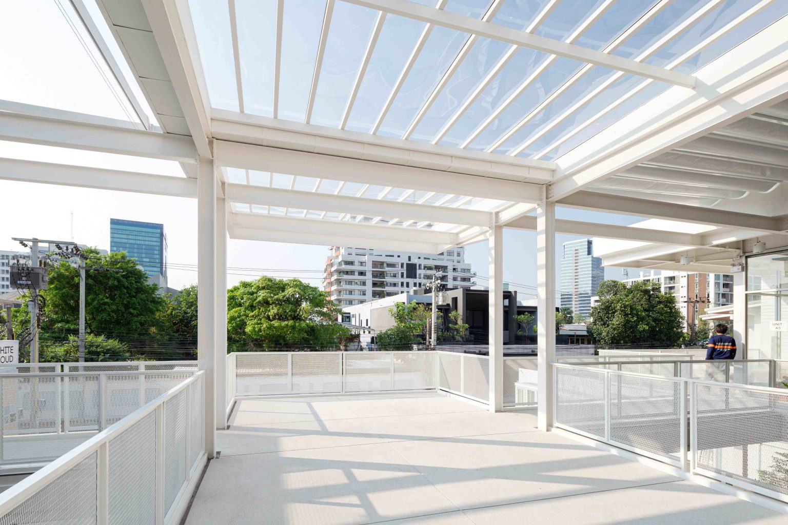 White Cloud Community Space – Community ฟีลบ้านเพื่อน ในพื้นที่บ้านเก่าอนุรักษ์และโครงสร้างใหม่จากเหล็ก SYS White Cloud Community Space เป็นการออกแบบพื้นที่ให้เช่าและ Community Space บนพื้นที่ย่านอารีย์ที่แต่เดิมมีบ้านหลังเก่าตั้งอยู่ โดยโจทย์ตั้งต้นคือการคงบ้านหลังเดิมที่มีความทรงจำและความสำคัญต่อเจ้าของที่ดินเอาไว้ สถาปนิกจึงทำการออกแบบพื้นที่ใช้งานใหม่โอบล้อมบ้านหลังเก่า เปลี่ยนบ้านเป็นไฮไลท์ และสร้างพื้นที่ใช้งานในร่มโอบล้อมโดยรอบ เพื่อให้ผู้คนเข้ามาใช้งานได้อย่างสะดวกสบายตลอดทั้งวัน ในพื้นที่อาคารประมาณ 1,200 ตารางเมตร (ไม่รวมพื้นที่จอดรถ) โครงการนี้ออกแบบโดย คุณอภิชัย จารุรัตนเกื้อ หรือคุณปริ้นท์ Architect Designer จาก Design to the Universe Co., Ltd. (บริษัท ดีไซน์ ทู เดอะ ยูนิเวิร์ส จำกัด) ผู้มีประสบการณ์ในการออกแบบงาน Commercial, Hospitality & Education Building ในหลากหลายโครงการ เช่น Holiday Pastry หน้าร้านชงดีที่ One Bangkok และ Central World หรือโรงพยาบาลหลายแห่ง เป็นผู้นำในการออกแบบ แบ่งสัดส่วนพื้นที่อย่างเป็นระบบ และสร้างเอกลักษณ์ให้กับแบรนด์ได้อย่างโดดเด่น ในโครงการ White Cloud Community Space ด้วยความต้องการให้ Space โปร่งโล่ง มีกรอบเวลาที่ชัดเจน และง่ายต่อการรื้อถอนหลังหมดสัญญาเช่า ทางสถาปนิกจึงเลือกใช้เหล็กโครงสร้าง H-BEAM จาก SYS เป็นโครงสร้างหลักของโครงการ เพราะมีคุณสมบัติที่ตอบโจทย์ทั้งงานดีไซน์ ความแข็งแรง และจัดการก่อสร้างได้สะดวก ส่งผลให้โครงการนี้เสร็จสิ้นได้รวดเร็ว มีดีไซน์ที่โปร่งโล่ง ไม่มีเสาโผล่กลางพื้นที่และตอบโจทย์เรื่องการรักษ์โลกได้จริง เป็น Community Space ยุคใหม่ ที่คุ้มค่าต่อเจ้าของโครงการในระยะยาว อีกทั้งยังสร้างความประทับใจ ความทรงจำ และประสบการณ์การใช้งานที่อบอุ่นและพิเศษให้กับผู้คนได้ทุกครั้งที่เข้ามาใช้งาน จากบ้านเก่าย่านอารีย์สู่ Community แห่งใหม่ในคอนเซ็ปต์ไข่แดง โครงการ White Cloud Community Space เริ่มต้นมาจากเจ้าของโครงการที่ต้องการเปลี่ยนบ้านเช่าหลังเก่าที่มีเอกลักษณ์เฉพาะตัวในย่านอารีย์ กรุงเทพมหานคร ให้กลายเป็น Commercial Building ที่ผู้คนสามารถเข้ามาใช้งานได้อย่างอิสระ ในขณะเดียวกันก็เปิดพื้นที่เช่าให้กับร้านค้าต่าง ๆ เข้ามาประกอบกิจกรรม ออกแบบโดยคุณอภิชัย จารุรัตนเกื้อ หรือคุณปริ้นท์ Architect Designer จาก Design to the Universe Co., Ltd. (บริษัท ดีไซน์ ทู เดอะ ยูนิเวิร์ส จำกัด) เดิมพื้นที่มีบ้านเก่า 2 ชั้นตั้งอยู่ และด้วยการเป็นพื้นที่เช่า เมื่อจบสัญญาเช่าเจ้าของโครงการจำเป็นต้องคืนพื้นที่ในสภาพเดิม ดังนั้นโครงการจึงเน้นไปที่การต่อเติมและสร้างโครงสร้างใหม่เข้ามาเสริม เพื่อรักษาโครงสร้างของบ้านเดิมเอาไว้ให้มากที่สุด และถือโอกาสชูบ้านหลังนี้ให้เป็นจุดเด่นของโครงการด้วย ทำให้บรรยากาศเสมือนการมานั่งเล่นที่บ้านเพื่อน เมื่อต้องการรักษาโครงสร้างเดิมของตัวบ้านเอาไว้ สถาปนิกจึงใช้การออกแบบและวางโครงสร้างส่วนใหม่เข้าไปรอบบ้านแทน เปรียบเสมือน “ไข่แดง (ตัวบ้านเดิม)” ที่ถูกล้อมรอบด้วย “ไข่ขาว (โครงสร้างใหม่)” โดยมีการวางพื้นที่จอดรถไว้ด้านหน้า ช่วยสร้างระยะการรับรู้จากถนน ให้ผู้ใช้งานสามารถมองเห็นความสวยงามของสถาปัตยกรรมและสัมผัสได้ถึงบรรยากาศสบาย ๆ ของโครงการได้ตั้งแต่ทางเข้า ส่วนตัวบ้านเดิมจะเป็นกระบวนการแบบ “กึ่งอนุรักษ์” คือพยายามรักษาวัสดุ โครงสร้างเดิมเอาไว้ เพื่อให้ความทรงจำของบ้านเด่นชัดและสื่อสารความรู้สึกแก่ผู้เข้ามาใช้งานได้อย่างชัดเจนที่สุด นอกจากนี้ยังใช้ “สวน” เพื่อแบ่งโซนการใช้งาน คือ สวนหน้าบ้าน เพิ่มความเขียวให้โครงการดูร่มรื่น และสวนหลังบ้านที่เป็นไฮไลท์ของโครงการ ที่มีร้านค้าหลากหลาย รวมถึงที่นั่ง บริเวณนี้จึงเกิดกิจกรรมและการเคลื่อนไหวค่อนข้างมาก เสริมให้โครงการมีชีวิตชีวามากขึ้น โครงการสีขาว เบาสบาย กับโจทย์ตั้งต้นที่โครงสร้างเหล็กกลายมาเป็นคำตอบ จากโจทย์หลักที่เป็นพื้นที่เช่า “โครงสร้างเหล็ก” จึงกลายเป็นคำตอบที่ชัดเจนสำหรับการออกแบบ เพราะโครงสร้างเหล็กสามารถต่อเติมได้สะดวกและรวดเร็วในพื้นที่ทุกขนาด เช่นเดียวกับโครงการนี้ที่ถนนหน้าโครงการค่อนข้างแคบ การเลือกความยาวเหล็กสำเร็จมาจากโรงงานทำให้การขนส่งเข้ามายังหน้างานเป็นไปอย่างราบรื่น อีกทั้งเหล็กยังสามารถติดตั้งได้รวดเร็ว ไม่กระทบโครงสร้างบ้านหลัก ตลอดจนไม่ก่อมลภาวะทางเสียงหรือฝุ่นให้กับบริบทข้างเคียงที่เป็นย่านที่พักอาศัย โดย White Cloud Community Space ใช้เวลาในการจัดการโครงสร้างเหล็กประมาณ 6 เดือนเท่านั้น (หากรวมระยะเวลาออกแบบจะใช้เวลา 9 เดือน) คุณปรินท์เล่าถึงความสำคัญของ “เวลา” ในโครงการประเภท Commercial Building ว่าโครงการประเภทนี้มักจะมีระยะเวลาในการเกิดชัดเจน ดังนั้นจึงเป็นเรื่องสำคัญมากในการเลือกใช้วัสดุให้เหมาะกับแบบที่คิดไว้และระยะเวลาที่มี ซึ่งเหล็ก H-BEAM จาก SYS ก็ตอบโจทย์ทั้งเรื่องระยะเวลาและรองรับรูปแบบของดีไซน์ที่ต้องการได้เป็นอย่างดี ไม่ว่าจะเป็นความโปร่ง เบา บางของโครงสร้าง เพื่อให้อาคารดูทันสมัย เท่เรียบง่าย แต่ไม่บดบังตัวตนของบ้านเดิม Span (ระยะห่างระหว่างเสา) ที่ยืดได้ยาวขึ้น เป็นอีกหนึ่งข้อดีของการเลือกใช้เหล็กเช่นกัน เมื่อเทียบกับโครงสร้างคอนกรีตที่ต้องมีการหล่อโครงสร้างเสาคาน อาจต้องมีคานทุก 4 เมตร ทำให้หนัาตัดคานอยู่ที่ประมาณ 40 – 50 เซนติเมตร (รวมความหนาคอนกรีตที่เททับด้านบนพื้น) แต่เมื่อเป็นโครงสร้างเหล็ก สามารถยืด Span ได้กว้างกว่าเดิม อีกทั้งในโครงการยังเลือกใช้โครงสร้าง Steel Truss ทำให้ยืดได้กว้างขึ้น ใช้จำนวนเสาในการรับน้ำหนักน้อยลง ส่งผลให้พื้นที่มีความโปร่งโล่งได้อย่างที่ต้องการ Highlight โถงสูงกลางบ้าน สร้างพื้นที่ให้กิจกรรมเชื่อมโยงถึงกัน สถาปนิกมองเผื่อไปยังอนาคตว่า ณ Community Space แห่งนี้อาจมีการขยายตัวของกิจกรรม เช่น การจัดคอนเสิร์ต จัดงานอีเวนต์ หรือทำการแสดงต่าง ๆ ซึ่งจะมีการรวมตัวของผู้คนจำนวนมาก ดังนั้นจึงเป็นแนวคิดที่ดีหากในโครงการมีพื้นที่โถงกลางเพื่อรองรับกิจกรรมนั้น โดยเมื่อเดินเข้ามาด้านในอาคาร จะเจอกับโถง Double Space ที่ฝ้าสูงประมาณ 7 – 8 เมตร มีพื้นที่ลานขนาดใหญ่ และมีการออกแบบเป็นอัฒจรรย์หรือ Amphitheater สีขาวขนาดใหญ่ที่สามารถใช้เป็นทั้งบันไดเชื่อมต่อไปยังชั้น 2 ของอาคารและใช้เป็นที่นั่งได้ ส่วนฝ้าเพดานออกแบบให้เป็นตารางรังผึ้ง มีการสลับกับช่องเปิดเพื่อนำแสงธรรมชาติลงมาสู่พื้นที่ผ่านหลังคาลอนคู่ใส 2 โทนสี คือ ลอนใสและลอนที่เคลือบสีเหลืองอบอุ่น ช่วยลดการเปิดไฟในตอนกลางวันและทำให้โถงสว่างเพียงพอต่อการใช้งาน อีกทั้งยังได้แสงที่นุ่มนวลและมีมิติมากขึ้น นอกจากนี้ยังมีการเติมรายละเอียดตามจุดต่าง ๆ ของอาคารเพื่อให้ภาพลักษณ์ สีสันที่ดูขาวสว่าง โปร่งโล่งนั้นเชื่อมโยงโดยทั่วกัน ผ่านดีไซน์ของขาโต๊ะที่ใช้เหล็ก H-BEAM นำมาตัดให้ได้ระยะใช้งานที่เหมาะสม หรือการเพิ่มฉากระแนงสีขาวแบ่งพื้นที่ใช้งานให้เป็นสัดส่วนแต่ยังคงเชื่อมโยงถึงกันผ่านการมองเห็น หลังคาที่ถูกยกความสูง เพิ่มความโปร่งให้ Space เหล็ก H-BEAM จาก SYS ไม่ได้ถูกใช้เป็นโครงสร้างของอาคารหลังใหม่เพียงเท่านั้น แต่ยังถูกใช้เพิ่มต่อเติมและเสริมให้บ้านเดิมมีความโปร่งโล่งแข็งแรงมากขึ้น ดีเทลหนึ่งที่น่าสนใจของโครงการ คือการใช้เหล็ก H-BEAM เข้ามายกความสูงของโครงสร้างหลังคาของบ้านเดิมขึ้น จากเดิมที่เพดานชั้นสองของบ้านค่อนข้างต่ำ เมื่อถูกรื้อฝ้าออกเพื่อโชว์ให้เห็น Slope ของโครงหลังคา ทำให้พื้นที่ภายในดูโปร่งมากขึ้น ส่วนของชั้นหนึ่งเองก็มีการยกเพดานขึ้นเช่นกัน โดยใช้โครงสร้างเหล็กต่อเข้ากับโครงสร้างคอนกรีตเดิมเพื่อพยุงโครงสร้างบ้านทั้งหมดให้มั่นคง อีกทั้งยังมีการรื้อฝ้าเพดานออกเพื่อให้พื้นที่ได้ความสูงโปร่งมากขึ้น โครงสร้างเหล็ก H-BEAM สีขาวที่ต่อเติมเข้ามามีความทันสมัยที่ตัดกับบรรยากาศบ้านโมเดิร์นที่ดูย้อนยุค ทำให้เกิด Contrast ของพื้นที่ที่น่าสนใจ เสมือนเดินเข้าสู่อาคารอนุรักษ์แบบร่วมสมัย เหล็ก = วัสดุที่ตอบโจทย์คุ้มค่าตั้งแต่วันแรกที่เลือกใช้ จนถึงวันสุดท้ายที่รื้อถอนอาคาร จากการที่ได้พูดคุยถึงขั้นตอนการคิด การออกแบบ และการก่อสร้างของโครงการ White Cloud Community Space กับคุณปรินท์ ทำให้ทราบว่า “สถาปนิก” หรือ “ผู้ออกแบบ” มีส่วนสำคัญที่ช่วยให้ความรู้ในเรื่องวัสดุที่เหมาะสมกับเจ้าของโครงการเป็นอย่างมาก เช่นเดียวกับในโครงการนี้ที่ทางคุณปรินท์ได้มีการเล่าเกี่ยวกับการเลือกใช้เหล็ก H-BEAM ที่นอกจากจะช่วยให้ภาพที่ออกแบบเป็นจริงตามที่ต้องการแล้ว ยังมีข้อดีอีกหลายอย่างในเชิงการใช้งาน เช่น ความรวดเร็ว ความเพรียวบางของโครงสร้าง เป็นโครงสร้างที่ไม่มีฝุ่น และที่สำคัญ คือในวันที่หมดสัญญาเช่า สามารถรื้อถอนได้ทันที สามารถขายหรือรีไซเคิลใช้งานต่อได้ ซึ่งทั้งหมดนี้ตอบโจทย์ความคุ้มค่าให้กับลูกค้าได้ในหลากหลายมุม ทั้งความใส่ใจของแบรนด์ที่มีต่ออาคารข้างเคียง และการคิดเผื่อด้านสิ่งแวดล้อมของโครงการซึ่งเป็นสิ่งที่ทั่วโลกต่างให้ความสำคัญอยู่ ณ เวลานี้ งานออกแบบที่สะท้อนให้เห็นความยืดหยุ่นในการใช้เหล็ก H-BEAM ในงานสถาปัตยกรรม (กึ่งอนุรักษ์ จากโครงการที่มีโครงสร้างบ้านเดิมอยู่แล้ว) และการก่อสร้าง ที่ช่วยสร้างเอกลักษณ์ให้กับโครงการ และตอบโจทย์หรือเงื่อนไขของโครงการได้อย่างตรงจุด ทั้งในเชิงความแข็งแรง ความสวยงาม และความยั่งยืน สนใจสินค้าเหล็ก H-BEAM และบริการจาก SYS สามารถติดต่อสอบถามได้ทางช่องทาง WEBSITE-SYS STEEL: https://bit.ly/3qYADQ0 YOUTUBE: http://bit.ly/3asNqnp LINE: https://bit.ly/3gEI0tz TikTok: https://bit.ly/46AnaTP White Cloud Community Space – Community ฟีลบ้านเพื่อน ในพื้นที่บ้านเก่าอนุรักษ์และโครงสร้างใหม่จากเหล็ก SYS White Cloud Community Space เป็นการออกแบบพื้นที่ให้เช่าและ Community Space บนพื้นที่ย่านอารีย์ที่แต่เดิมมีบ้านหลังเก่าตั้งอยู่ โดยโจทย์ตั้งต้นคือการคงบ้านหลังเดิมที่มีความทรงจำและความสำคัญต่อเจ้าของที่ดินเอาไว้ สถาปนิกจึงทำการออกแบบพื้นที่ใช้งานใหม่โอบล้อมบ้านหลังเก่า เปลี่ยนบ้านเป็นไฮไลท์ และสร้างพื้นที่ใช้งานในร่มโอบล้อมโดยรอบ เพื่อให้ผู้คนเข้ามาใช้งานได้อย่างสะดวกสบายตลอดทั้งวัน ในพื้นที่อาคารประมาณ 1,200 ตารางเมตร (ไม่รวมพื้นที่จอดรถ) โครงการนี้ออกแบบโดย คุณอภิชัย จารุรัตนเกื้อ หรือคุณปริ้นท์ Architect Designer จาก Design to the Universe Co., Ltd. (บริษัท ดีไซน์ ทู เดอะ ยูนิเวิร์ส จำกัด) ผู้มีประสบการณ์ในการออกแบบงาน Commercial, Hospitality & Education Building ในหลากหลายโครงการ เช่น Holiday Pastry หน้าร้านชงดีที่ One Bangkok และ Central World หรือโรงพยาบาลหลายแห่ง เป็นผู้นำในการออกแบบ แบ่งสัดส่วนพื้นที่อย่างเป็นระบบ และสร้างเอกลักษณ์ให้กับแบรนด์ได้อย่างโดดเด่น ในโครงการ White Cloud Community Space ด้วยความต้องการให้ Space โปร่งโล่ง มีกรอบเวลาที่ชัดเจน และง่ายต่อการรื้อถอนหลังหมดสัญญาเช่า ทางสถาปนิกจึงเลือกใช้เหล็กโครงสร้าง H-BEAM จาก SYS เป็นโครงสร้างหลักของโครงการ เพราะมีคุณสมบัติที่ตอบโจทย์ทั้งงานดีไซน์ ความแข็งแรง และจัดการก่อสร้างได้สะดวก ส่งผลให้โครงการนี้เสร็จสิ้นได้รวดเร็ว มีดีไซน์ที่โปร่งโล่ง ไม่มีเสาโผล่กลางพื้นที่และตอบโจทย์เรื่องการรักษ์โลกได้จริง เป็น Community Space ยุคใหม่ ที่คุ้มค่าต่อเจ้าของโครงการในระยะยาว อีกทั้งยังสร้างความประทับใจ ความทรงจำ และประสบการณ์การใช้งานที่อบอุ่นและพิเศษให้กับผู้คนได้ทุกครั้งที่เข้ามาใช้งาน จากบ้านเก่าย่านอารีย์สู่ Community แห่งใหม่ในคอนเซ็ปต์ไข่แดง โครงการ White Cloud Community Space เริ่มต้นมาจากเจ้าของโครงการที่ต้องการเปลี่ยนบ้านเช่าหลังเก่าที่มีเอกลักษณ์เฉพาะตัวในย่านอารีย์ กรุงเทพมหานคร ให้กลายเป็น Commercial Building ที่ผู้คนสามารถเข้ามาใช้งานได้อย่างอิสระ ในขณะเดียวกันก็เปิดพื้นที่เช่าให้กับร้านค้าต่าง ๆ เข้ามาประกอบกิจกรรม ออกแบบโดยคุณอภิชัย จารุรัตนเกื้อ หรือคุณปริ้นท์ Architect Designer จาก Design to the Universe Co., Ltd. (บริษัท ดีไซน์ ทู เดอะ ยูนิเวิร์ส จำกัด) เดิมพื้นที่มีบ้านเก่า 2 ชั้นตั้งอยู่ และด้วยการเป็นพื้นที่เช่า เมื่อจบสัญญาเช่าเจ้าของโครงการจำเป็นต้องคืนพื้นที่ในสภาพเดิม ดังนั้นโครงการจึงเน้นไปที่การต่อเติมและสร้างโครงสร้างใหม่เข้ามาเสริม เพื่อรักษาโครงสร้างของบ้านเดิมเอาไว้ให้มากที่สุด และถือโอกาสชูบ้านหลังนี้ให้เป็นจุดเด่นของโครงการด้วย ทำให้บรรยากาศเสมือนการมานั่งเล่นที่บ้านเพื่อน เมื่อต้องการรักษาโครงสร้างเดิมของตัวบ้านเอาไว้ สถาปนิกจึงใช้การออกแบบและวางโครงสร้างส่วนใหม่เข้าไปรอบบ้านแทน เปรียบเสมือน “ไข่แดง (ตัวบ้านเดิม)” ที่ถูกล้อมรอบด้วย “ไข่ขาว (โครงสร้างใหม่)” โดยมีการวางพื้นที่จอดรถไว้ด้านหน้า ช่วยสร้างระยะการรับรู้จากถนน ให้ผู้ใช้งานสามารถมองเห็นความสวยงามของสถาปัตยกรรมและสัมผัสได้ถึงบรรยากาศสบาย ๆ ของโครงการได้ตั้งแต่ทางเข้า ส่วนตัวบ้านเดิมจะเป็นกระบวนการแบบ “กึ่งอนุรักษ์” คือพยายามรักษาวัสดุ โครงสร้างเดิมเอาไว้ เพื่อให้ความทรงจำของบ้านเด่นชัดและสื่อสารความรู้สึกแก่ผู้เข้ามาใช้งานได้อย่างชัดเจนที่สุด นอกจากนี้ยังใช้ “สวน” เพื่อแบ่งโซนการใช้งาน คือ สวนหน้าบ้าน เพิ่มความเขียวให้โครงการดูร่มรื่น และสวนหลังบ้านที่เป็นไฮไลท์ของโครงการ ที่มีร้านค้าหลากหลาย รวมถึงที่นั่ง บริเวณนี้จึงเกิดกิจกรรมและการเคลื่อนไหวค่อนข้างมาก เสริมให้โครงการมีชีวิตชีวามากขึ้น โครงการสีขาว เบาสบาย กับโจทย์ตั้งต้นที่โครงสร้างเหล็กกลายมาเป็นคำตอบ จากโจทย์หลักที่เป็นพื้นที่เช่า “โครงสร้างเหล็ก” จึงกลายเป็นคำตอบที่ชัดเจนสำหรับการออกแบบ เพราะโครงสร้างเหล็กสามารถต่อเติมได้สะดวกและรวดเร็วในพื้นที่ทุกขนาด เช่นเดียวกับโครงการนี้ที่ถนนหน้าโครงการค่อนข้างแคบ การเลือกความยาวเหล็กสำเร็จมาจากโรงงานทำให้การขนส่งเข้ามายังหน้างานเป็นไปอย่างราบรื่น อีกทั้งเหล็กยังสามารถติดตั้งได้รวดเร็ว ไม่กระทบโครงสร้างบ้านหลัก ตลอดจนไม่ก่อมลภาวะทางเสียงหรือฝุ่นให้กับบริบทข้างเคียงที่เป็นย่านที่พักอาศัย โดย White Cloud Community Space ใช้เวลาในการจัดการโครงสร้างเหล็กประมาณ 6 เดือนเท่านั้น (หากรวมระยะเวลาออกแบบจะใช้เวลา 9 เดือน) คุณปรินท์เล่าถึงความสำคัญของ “เวลา” ในโครงการประเภท Commercial Building ว่าโครงการประเภทนี้มักจะมีระยะเวลาในการเกิดชัดเจน ดังนั้นจึงเป็นเรื่องสำคัญมากในการเลือกใช้วัสดุให้เหมาะกับแบบที่คิดไว้และระยะเวลาที่มี ซึ่งเหล็ก H-BEAM จาก SYS ก็ตอบโจทย์ทั้งเรื่องระยะเวลาและรองรับรูปแบบของดีไซน์ที่ต้องการได้เป็นอย่างดี ไม่ว่าจะเป็นความโปร่ง เบา บางของโครงสร้าง เพื่อให้อาคารดูทันสมัย เท่เรียบง่าย แต่ไม่บดบังตัวตนของบ้านเดิม Span (ระยะห่างระหว่างเสา) ที่ยืดได้ยาวขึ้น เป็นอีกหนึ่งข้อดีของการเลือกใช้เหล็กเช่นกัน เมื่อเทียบกับโครงสร้างคอนกรีตที่ต้องมีการหล่อโครงสร้างเสาคาน อาจต้องมีคานทุก 4 เมตร ทำให้หนัาตัดคานอยู่ที่ประมาณ 40 – 50 เซนติเมตร (รวมความหนาคอนกรีตที่เททับด้านบนพื้น) แต่เมื่อเป็นโครงสร้างเหล็ก สามารถยืด Span ได้กว้างกว่าเดิม อีกทั้งในโครงการยังเลือกใช้โครงสร้าง Steel Truss ทำให้ยืดได้กว้างขึ้น ใช้จำนวนเสาในการรับน้ำหนักน้อยลง ส่งผลให้พื้นที่มีความโปร่งโล่งได้อย่างที่ต้องการ Highlight โถงสูงกลางบ้าน สร้างพื้นที่ให้กิจกรรมเชื่อมโยงถึงกัน สถาปนิกมองเผื่อไปยังอนาคตว่า ณ Community Space แห่งนี้อาจมีการขยายตัวของกิจกรรม เช่น การจัดคอนเสิร์ต จัดงานอีเวนต์ หรือทำการแสดงต่าง ๆ ซึ่งจะมีการรวมตัวของผู้คนจำนวนมาก ดังนั้นจึงเป็นแนวคิดที่ดีหากในโครงการมีพื้นที่โถงกลางเพื่อรองรับกิจกรรมนั้น โดยเมื่อเดินเข้ามาด้านในอาคาร จะเจอกับโถง Double Space ที่ฝ้าสูงประมาณ 7 – 8 เมตร มีพื้นที่ลานขนาดใหญ่ และมีการออกแบบเป็นอัฒจรรย์หรือ Amphitheater สีขาวขนาดใหญ่ที่สามารถใช้เป็นทั้งบันไดเชื่อมต่อไปยังชั้น 2 ของอาคารและใช้เป็นที่นั่งได้ ส่วนฝ้าเพดานออกแบบให้เป็นตารางรังผึ้ง มีการสลับกับช่องเปิดเพื่อนำแสงธรรมชาติลงมาสู่พื้นที่ผ่านหลังคาลอนคู่ใส 2 โทนสี คือ ลอนใสและลอนที่เคลือบสีเหลืองอบอุ่น ช่วยลดการเปิดไฟในตอนกลางวันและทำให้โถงสว่างเพียงพอต่อการใช้งาน อีกทั้งยังได้แสงที่นุ่มนวลและมีมิติมากขึ้น นอกจากนี้ยังมีการเติมรายละเอียดตามจุดต่าง ๆ ของอาคารเพื่อให้ภาพลักษณ์ สีสันที่ดูขาวสว่าง โปร่งโล่งนั้นเชื่อมโยงโดยทั่วกัน ผ่านดีไซน์ของขาโต๊ะที่ใช้เหล็ก H-BEAM นำมาตัดให้ได้ระยะใช้งานที่เหมาะสม หรือการเพิ่มฉากระแนงสีขาวแบ่งพื้นที่ใช้งานให้เป็นสัดส่วนแต่ยังคงเชื่อมโยงถึงกันผ่านการมองเห็น หลังคาที่ถูกยกความสูง เพิ่มความโปร่งให้ Space เหล็ก H-BEAM จาก SYS ไม่ได้ถูกใช้เป็นโครงสร้างของอาคารหลังใหม่เพียงเท่านั้น แต่ยังถูกใช้เพิ่มต่อเติมและเสริมให้บ้านเดิมมีความโปร่งโล่งแข็งแรงมากขึ้น ดีเทลหนึ่งที่น่าสนใจของโครงการ คือการใช้เหล็ก H-BEAM เข้ามายกความสูงของโครงสร้างหลังคาของบ้านเดิมขึ้น จากเดิมที่เพดานชั้นสองของบ้านค่อนข้างต่ำ เมื่อถูกรื้อฝ้าออกเพื่อโชว์ให้เห็น Slope ของโครงหลังคา ทำให้พื้นที่ภายในดูโปร่งมากขึ้น ส่วนของชั้นหนึ่งเองก็มีการยกเพดานขึ้นเช่นกัน โดยใช้โครงสร้างเหล็กต่อเข้ากับโครงสร้างคอนกรีตเดิมเพื่อพยุงโครงสร้างบ้านทั้งหมดให้มั่นคง อีกทั้งยังมีการรื้อฝ้าเพดานออกเพื่อให้พื้นที่ได้ความสูงโปร่งมากขึ้น โครงสร้างเหล็ก H-BEAM สีขาวที่ต่อเติมเข้ามามีความทันสมัยที่ตัดกับบรรยากาศบ้านโมเดิร์นที่ดูย้อนยุค ทำให้เกิด Contrast ของพื้นที่ที่น่าสนใจ เสมือนเดินเข้าสู่อาคารอนุรักษ์แบบร่วมสมัย เหล็ก = วัสดุที่ตอบโจทย์คุ้มค่าตั้งแต่วันแรกที่เลือกใช้ จนถึงวันสุดท้ายที่รื้อถอนอาคาร จากการที่ได้พูดคุยถึงขั้นตอนการคิด การออกแบบ และการก่อสร้างของโครงการ White Cloud Community Space กับคุณปรินท์ ทำให้ทราบว่า “สถาปนิก” หรือ “ผู้ออกแบบ” มีส่วนสำคัญที่ช่วยให้ความรู้ในเรื่องวัสดุที่เหมาะสมกับเจ้าของโครงการเป็นอย่างมาก เช่นเดียวกับในโครงการนี้ที่ทางคุณปรินท์ได้มีการเล่าเกี่ยวกับการเลือกใช้เหล็ก H-BEAM ที่นอกจากจะช่วยให้ภาพที่ออกแบบเป็นจริงตามที่ต้องการแล้ว ยังมีข้อดีอีกหลายอย่างในเชิงการใช้งาน เช่น ความรวดเร็ว ความเพรียวบางของโครงสร้าง เป็นโครงสร้างที่ไม่มีฝุ่น และที่สำคัญ คือในวันที่หมดสัญญาเช่า สามารถรื้อถอนได้ทันที สามารถขายหรือรีไซเคิลใช้งานต่อได้ ซึ่งทั้งหมดนี้ตอบโจทย์ความคุ้มค่าให้กับลูกค้าได้ในหลากหลายมุม ทั้งความใส่ใจของแบรนด์ที่มีต่ออาคารข้างเคียง และการคิดเผื่อด้านสิ่งแวดล้อมของโครงการซึ่งเป็นสิ่งที่ทั่วโลกต่างให้ความสำคัญอยู่ ณ เวลานี้ งานออกแบบที่สะท้อนให้เห็นความยืดหยุ่นในการใช้เหล็ก H-BEAM ในงานสถาปัตยกรรม (กึ่งอนุรักษ์ จากโครงการที่มีโครงสร้างบ้านเดิมอยู่แล้ว) และการก่อสร้าง ที่ช่วยสร้างเอกลักษณ์ให้กับโครงการ และตอบโจทย์หรือเงื่อนไขของโครงการได้อย่างตรงจุด ทั้งในเชิงความแข็งแรง ความสวยงาม และความยั่งยืน สนใจสินค้าเหล็ก H-BEAM และบริการจาก SYS สามารถติดต่อสอบถามได้ทางช่องทาง WEBSITE-SYS STEEL: https://bit.ly/3qYADQ0 YOUTUBE: http://bit.ly/3asNqnp LINE: https://bit.ly/3gEI0tz TikTok: https://bit.ly/46AnaTP
