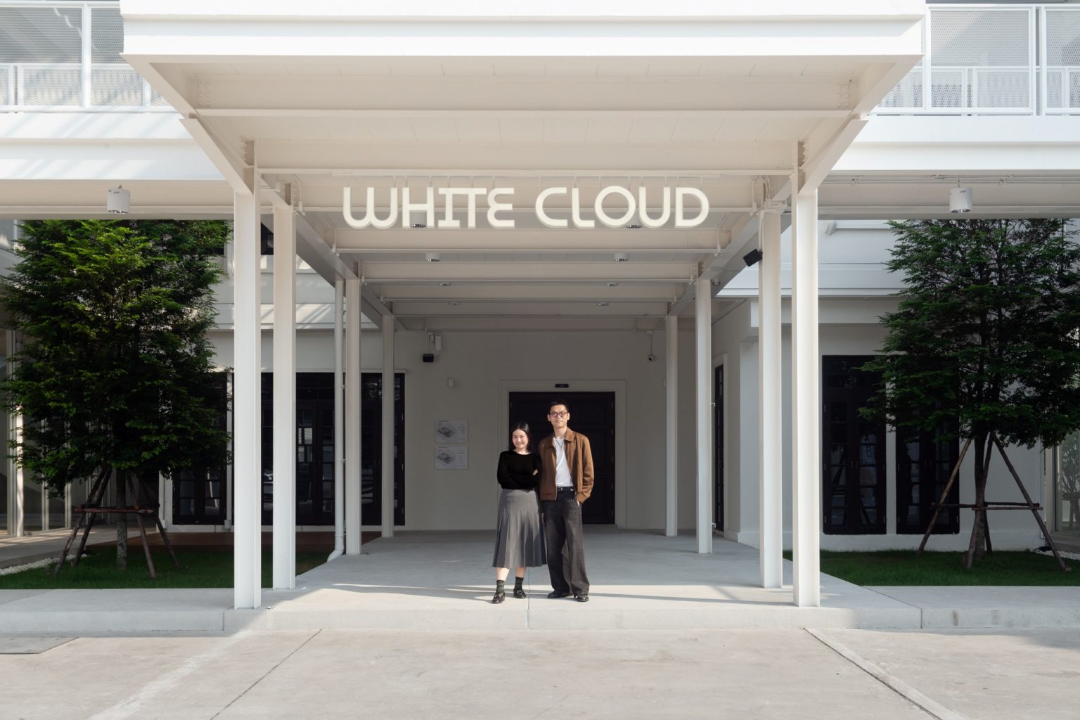 White Cloud Community Space – Community ฟีลบ้านเพื่อน ในพื้นที่บ้านเก่าอนุรักษ์และโครงสร้างใหม่จากเหล็ก SYS White Cloud Community Space เป็นการออกแบบพื้นที่ให้เช่าและ Community Space บนพื้นที่ย่านอารีย์ที่แต่เดิมมีบ้านหลังเก่าตั้งอยู่ โดยโจทย์ตั้งต้นคือการคงบ้านหลังเดิมที่มีความทรงจำและความสำคัญต่อเจ้าของที่ดินเอาไว้ สถาปนิกจึงทำการออกแบบพื้นที่ใช้งานใหม่โอบล้อมบ้านหลังเก่า เปลี่ยนบ้านเป็นไฮไลท์ และสร้างพื้นที่ใช้งานในร่มโอบล้อมโดยรอบ เพื่อให้ผู้คนเข้ามาใช้งานได้อย่างสะดวกสบายตลอดทั้งวัน ในพื้นที่อาคารประมาณ 1,200 ตารางเมตร (ไม่รวมพื้นที่จอดรถ) โครงการนี้ออกแบบโดย คุณอภิชัย จารุรัตนเกื้อ หรือคุณปริ้นท์ Architect Designer จาก Design to the Universe Co., Ltd. (บริษัท ดีไซน์ ทู เดอะ ยูนิเวิร์ส จำกัด) ผู้มีประสบการณ์ในการออกแบบงาน Commercial, Hospitality & Education Building ในหลากหลายโครงการ เช่น Holiday Pastry หน้าร้านชงดีที่ One Bangkok และ Central World หรือโรงพยาบาลหลายแห่ง เป็นผู้นำในการออกแบบ แบ่งสัดส่วนพื้นที่อย่างเป็นระบบ และสร้างเอกลักษณ์ให้กับแบรนด์ได้อย่างโดดเด่น ในโครงการ White Cloud Community Space ด้วยความต้องการให้ Space โปร่งโล่ง มีกรอบเวลาที่ชัดเจน และง่ายต่อการรื้อถอนหลังหมดสัญญาเช่า ทางสถาปนิกจึงเลือกใช้เหล็กโครงสร้าง H-BEAM จาก SYS เป็นโครงสร้างหลักของโครงการ เพราะมีคุณสมบัติที่ตอบโจทย์ทั้งงานดีไซน์ ความแข็งแรง และจัดการก่อสร้างได้สะดวก ส่งผลให้โครงการนี้เสร็จสิ้นได้รวดเร็ว มีดีไซน์ที่โปร่งโล่ง ไม่มีเสาโผล่กลางพื้นที่และตอบโจทย์เรื่องการรักษ์โลกได้จริง เป็น Community Space ยุคใหม่ ที่คุ้มค่าต่อเจ้าของโครงการในระยะยาว อีกทั้งยังสร้างความประทับใจ ความทรงจำ และประสบการณ์การใช้งานที่อบอุ่นและพิเศษให้กับผู้คนได้ทุกครั้งที่เข้ามาใช้งาน จากบ้านเก่าย่านอารีย์สู่ Community แห่งใหม่ในคอนเซ็ปต์ไข่แดง โครงการ White Cloud Community Space เริ่มต้นมาจากเจ้าของโครงการที่ต้องการเปลี่ยนบ้านเช่าหลังเก่าที่มีเอกลักษณ์เฉพาะตัวในย่านอารีย์ กรุงเทพมหานคร ให้กลายเป็น Commercial Building ที่ผู้คนสามารถเข้ามาใช้งานได้อย่างอิสระ ในขณะเดียวกันก็เปิดพื้นที่เช่าให้กับร้านค้าต่าง ๆ เข้ามาประกอบกิจกรรม ออกแบบโดยคุณอภิชัย จารุรัตนเกื้อ หรือคุณปริ้นท์ Architect Designer จาก Design to the Universe Co., Ltd. (บริษัท ดีไซน์ ทู เดอะ ยูนิเวิร์ส จำกัด) เดิมพื้นที่มีบ้านเก่า 2 ชั้นตั้งอยู่ และด้วยการเป็นพื้นที่เช่า เมื่อจบสัญญาเช่าเจ้าของโครงการจำเป็นต้องคืนพื้นที่ในสภาพเดิม ดังนั้นโครงการจึงเน้นไปที่การต่อเติมและสร้างโครงสร้างใหม่เข้ามาเสริม เพื่อรักษาโครงสร้างของบ้านเดิมเอาไว้ให้มากที่สุด และถือโอกาสชูบ้านหลังนี้ให้เป็นจุดเด่นของโครงการด้วย ทำให้บรรยากาศเสมือนการมานั่งเล่นที่บ้านเพื่อน เมื่อต้องการรักษาโครงสร้างเดิมของตัวบ้านเอาไว้ สถาปนิกจึงใช้การออกแบบและวางโครงสร้างส่วนใหม่เข้าไปรอบบ้านแทน เปรียบเสมือน “ไข่แดง (ตัวบ้านเดิม)” ที่ถูกล้อมรอบด้วย “ไข่ขาว (โครงสร้างใหม่)” โดยมีการวางพื้นที่จอดรถไว้ด้านหน้า ช่วยสร้างระยะการรับรู้จากถนน ให้ผู้ใช้งานสามารถมองเห็นความสวยงามของสถาปัตยกรรมและสัมผัสได้ถึงบรรยากาศสบาย ๆ ของโครงการได้ตั้งแต่ทางเข้า ส่วนตัวบ้านเดิมจะเป็นกระบวนการแบบ “กึ่งอนุรักษ์” คือพยายามรักษาวัสดุ โครงสร้างเดิมเอาไว้ เพื่อให้ความทรงจำของบ้านเด่นชัดและสื่อสารความรู้สึกแก่ผู้เข้ามาใช้งานได้อย่างชัดเจนที่สุด นอกจากนี้ยังใช้ “สวน” เพื่อแบ่งโซนการใช้งาน คือ สวนหน้าบ้าน เพิ่มความเขียวให้โครงการดูร่มรื่น และสวนหลังบ้านที่เป็นไฮไลท์ของโครงการ ที่มีร้านค้าหลากหลาย รวมถึงที่นั่ง บริเวณนี้จึงเกิดกิจกรรมและการเคลื่อนไหวค่อนข้างมาก เสริมให้โครงการมีชีวิตชีวามากขึ้น โครงการสีขาว เบาสบาย กับโจทย์ตั้งต้นที่โครงสร้างเหล็กกลายมาเป็นคำตอบ จากโจทย์หลักที่เป็นพื้นที่เช่า “โครงสร้างเหล็ก” จึงกลายเป็นคำตอบที่ชัดเจนสำหรับการออกแบบ เพราะโครงสร้างเหล็กสามารถต่อเติมได้สะดวกและรวดเร็วในพื้นที่ทุกขนาด เช่นเดียวกับโครงการนี้ที่ถนนหน้าโครงการค่อนข้างแคบ การเลือกความยาวเหล็กสำเร็จมาจากโรงงานทำให้การขนส่งเข้ามายังหน้างานเป็นไปอย่างราบรื่น อีกทั้งเหล็กยังสามารถติดตั้งได้รวดเร็ว ไม่กระทบโครงสร้างบ้านหลัก ตลอดจนไม่ก่อมลภาวะทางเสียงหรือฝุ่นให้กับบริบทข้างเคียงที่เป็นย่านที่พักอาศัย โดย White Cloud Community Space ใช้เวลาในการจัดการโครงสร้างเหล็กประมาณ 6 เดือนเท่านั้น (หากรวมระยะเวลาออกแบบจะใช้เวลา 9 เดือน) คุณปรินท์เล่าถึงความสำคัญของ “เวลา” ในโครงการประเภท Commercial Building ว่าโครงการประเภทนี้มักจะมีระยะเวลาในการเกิดชัดเจน ดังนั้นจึงเป็นเรื่องสำคัญมากในการเลือกใช้วัสดุให้เหมาะกับแบบที่คิดไว้และระยะเวลาที่มี ซึ่งเหล็ก H-BEAM จาก SYS ก็ตอบโจทย์ทั้งเรื่องระยะเวลาและรองรับรูปแบบของดีไซน์ที่ต้องการได้เป็นอย่างดี ไม่ว่าจะเป็นความโปร่ง เบา บางของโครงสร้าง เพื่อให้อาคารดูทันสมัย เท่เรียบง่าย แต่ไม่บดบังตัวตนของบ้านเดิม Span (ระยะห่างระหว่างเสา) ที่ยืดได้ยาวขึ้น เป็นอีกหนึ่งข้อดีของการเลือกใช้เหล็กเช่นกัน เมื่อเทียบกับโครงสร้างคอนกรีตที่ต้องมีการหล่อโครงสร้างเสาคาน อาจต้องมีคานทุก 4 เมตร ทำให้หนัาตัดคานอยู่ที่ประมาณ 40 – 50 เซนติเมตร (รวมความหนาคอนกรีตที่เททับด้านบนพื้น) แต่เมื่อเป็นโครงสร้างเหล็ก สามารถยืด Span ได้กว้างกว่าเดิม อีกทั้งในโครงการยังเลือกใช้โครงสร้าง Steel Truss ทำให้ยืดได้กว้างขึ้น ใช้จำนวนเสาในการรับน้ำหนักน้อยลง ส่งผลให้พื้นที่มีความโปร่งโล่งได้อย่างที่ต้องการ Highlight โถงสูงกลางบ้าน สร้างพื้นที่ให้กิจกรรมเชื่อมโยงถึงกัน สถาปนิกมองเผื่อไปยังอนาคตว่า ณ Community Space แห่งนี้อาจมีการขยายตัวของกิจกรรม เช่น การจัดคอนเสิร์ต จัดงานอีเวนต์ หรือทำการแสดงต่าง ๆ ซึ่งจะมีการรวมตัวของผู้คนจำนวนมาก ดังนั้นจึงเป็นแนวคิดที่ดีหากในโครงการมีพื้นที่โถงกลางเพื่อรองรับกิจกรรมนั้น โดยเมื่อเดินเข้ามาด้านในอาคาร จะเจอกับโถง Double Space ที่ฝ้าสูงประมาณ 7 – 8 เมตร มีพื้นที่ลานขนาดใหญ่ และมีการออกแบบเป็นอัฒจรรย์หรือ Amphitheater สีขาวขนาดใหญ่ที่สามารถใช้เป็นทั้งบันไดเชื่อมต่อไปยังชั้น 2 ของอาคารและใช้เป็นที่นั่งได้ ส่วนฝ้าเพดานออกแบบให้เป็นตารางรังผึ้ง มีการสลับกับช่องเปิดเพื่อนำแสงธรรมชาติลงมาสู่พื้นที่ผ่านหลังคาลอนคู่ใส 2 โทนสี คือ ลอนใสและลอนที่เคลือบสีเหลืองอบอุ่น ช่วยลดการเปิดไฟในตอนกลางวันและทำให้โถงสว่างเพียงพอต่อการใช้งาน อีกทั้งยังได้แสงที่นุ่มนวลและมีมิติมากขึ้น นอกจากนี้ยังมีการเติมรายละเอียดตามจุดต่าง ๆ ของอาคารเพื่อให้ภาพลักษณ์ สีสันที่ดูขาวสว่าง โปร่งโล่งนั้นเชื่อมโยงโดยทั่วกัน ผ่านดีไซน์ของขาโต๊ะที่ใช้เหล็ก H-BEAM นำมาตัดให้ได้ระยะใช้งานที่เหมาะสม หรือการเพิ่มฉากระแนงสีขาวแบ่งพื้นที่ใช้งานให้เป็นสัดส่วนแต่ยังคงเชื่อมโยงถึงกันผ่านการมองเห็น หลังคาที่ถูกยกความสูง เพิ่มความโปร่งให้ Space เหล็ก H-BEAM จาก SYS ไม่ได้ถูกใช้เป็นโครงสร้างของอาคารหลังใหม่เพียงเท่านั้น แต่ยังถูกใช้เพิ่มต่อเติมและเสริมให้บ้านเดิมมีความโปร่งโล่งแข็งแรงมากขึ้น ดีเทลหนึ่งที่น่าสนใจของโครงการ คือการใช้เหล็ก H-BEAM เข้ามายกความสูงของโครงสร้างหลังคาของบ้านเดิมขึ้น จากเดิมที่เพดานชั้นสองของบ้านค่อนข้างต่ำ เมื่อถูกรื้อฝ้าออกเพื่อโชว์ให้เห็น Slope ของโครงหลังคา ทำให้พื้นที่ภายในดูโปร่งมากขึ้น ส่วนของชั้นหนึ่งเองก็มีการยกเพดานขึ้นเช่นกัน โดยใช้โครงสร้างเหล็กต่อเข้ากับโครงสร้างคอนกรีตเดิมเพื่อพยุงโครงสร้างบ้านทั้งหมดให้มั่นคง อีกทั้งยังมีการรื้อฝ้าเพดานออกเพื่อให้พื้นที่ได้ความสูงโปร่งมากขึ้น โครงสร้างเหล็ก H-BEAM สีขาวที่ต่อเติมเข้ามามีความทันสมัยที่ตัดกับบรรยากาศบ้านโมเดิร์นที่ดูย้อนยุค ทำให้เกิด Contrast ของพื้นที่ที่น่าสนใจ เสมือนเดินเข้าสู่อาคารอนุรักษ์แบบร่วมสมัย เหล็ก = วัสดุที่ตอบโจทย์คุ้มค่าตั้งแต่วันแรกที่เลือกใช้ จนถึงวันสุดท้ายที่รื้อถอนอาคาร จากการที่ได้พูดคุยถึงขั้นตอนการคิด การออกแบบ และการก่อสร้างของโครงการ White Cloud Community Space กับคุณปรินท์ ทำให้ทราบว่า “สถาปนิก” หรือ “ผู้ออกแบบ” มีส่วนสำคัญที่ช่วยให้ความรู้ในเรื่องวัสดุที่เหมาะสมกับเจ้าของโครงการเป็นอย่างมาก เช่นเดียวกับในโครงการนี้ที่ทางคุณปรินท์ได้มีการเล่าเกี่ยวกับการเลือกใช้เหล็ก H-BEAM ที่นอกจากจะช่วยให้ภาพที่ออกแบบเป็นจริงตามที่ต้องการแล้ว ยังมีข้อดีอีกหลายอย่างในเชิงการใช้งาน เช่น ความรวดเร็ว ความเพรียวบางของโครงสร้าง เป็นโครงสร้างที่ไม่มีฝุ่น และที่สำคัญ คือในวันที่หมดสัญญาเช่า สามารถรื้อถอนได้ทันที สามารถขายหรือรีไซเคิลใช้งานต่อได้ ซึ่งทั้งหมดนี้ตอบโจทย์ความคุ้มค่าให้กับลูกค้าได้ในหลากหลายมุม ทั้งความใส่ใจของแบรนด์ที่มีต่ออาคารข้างเคียง และการคิดเผื่อด้านสิ่งแวดล้อมของโครงการซึ่งเป็นสิ่งที่ทั่วโลกต่างให้ความสำคัญอยู่ ณ เวลานี้ งานออกแบบที่สะท้อนให้เห็นความยืดหยุ่นในการใช้เหล็ก H-BEAM ในงานสถาปัตยกรรม (กึ่งอนุรักษ์ จากโครงการที่มีโครงสร้างบ้านเดิมอยู่แล้ว) และการก่อสร้าง ที่ช่วยสร้างเอกลักษณ์ให้กับโครงการ และตอบโจทย์หรือเงื่อนไขของโครงการได้อย่างตรงจุด ทั้งในเชิงความแข็งแรง ความสวยงาม และความยั่งยืน สนใจสินค้าเหล็ก H-BEAM และบริการจาก SYS สามารถติดต่อสอบถามได้ทางช่องทาง WEBSITE-SYS STEEL: https://bit.ly/3qYADQ0 YOUTUBE: http://bit.ly/3asNqnp LINE: https://bit.ly/3gEI0tz TikTok: https://bit.ly/46AnaTP White Cloud Community Space – Community ฟีลบ้านเพื่อน ในพื้นที่บ้านเก่าอนุรักษ์และโครงสร้างใหม่จากเหล็ก SYS White Cloud Community Space เป็นการออกแบบพื้นที่ให้เช่าและ Community Space บนพื้นที่ย่านอารีย์ที่แต่เดิมมีบ้านหลังเก่าตั้งอยู่ โดยโจทย์ตั้งต้นคือการคงบ้านหลังเดิมที่มีความทรงจำและความสำคัญต่อเจ้าของที่ดินเอาไว้ สถาปนิกจึงทำการออกแบบพื้นที่ใช้งานใหม่โอบล้อมบ้านหลังเก่า เปลี่ยนบ้านเป็นไฮไลท์ และสร้างพื้นที่ใช้งานในร่มโอบล้อมโดยรอบ เพื่อให้ผู้คนเข้ามาใช้งานได้อย่างสะดวกสบายตลอดทั้งวัน ในพื้นที่อาคารประมาณ 1,200 ตารางเมตร (ไม่รวมพื้นที่จอดรถ) โครงการนี้ออกแบบโดย คุณอภิชัย จารุรัตนเกื้อ หรือคุณปริ้นท์ Architect Designer จาก Design to the Universe Co., Ltd. (บริษัท ดีไซน์ ทู เดอะ ยูนิเวิร์ส จำกัด) ผู้มีประสบการณ์ในการออกแบบงาน Commercial, Hospitality & Education Building ในหลากหลายโครงการ เช่น Holiday Pastry หน้าร้านชงดีที่ One Bangkok และ Central World หรือโรงพยาบาลหลายแห่ง เป็นผู้นำในการออกแบบ แบ่งสัดส่วนพื้นที่อย่างเป็นระบบ และสร้างเอกลักษณ์ให้กับแบรนด์ได้อย่างโดดเด่น ในโครงการ White Cloud Community Space ด้วยความต้องการให้ Space โปร่งโล่ง มีกรอบเวลาที่ชัดเจน และง่ายต่อการรื้อถอนหลังหมดสัญญาเช่า ทางสถาปนิกจึงเลือกใช้เหล็กโครงสร้าง H-BEAM จาก SYS เป็นโครงสร้างหลักของโครงการ เพราะมีคุณสมบัติที่ตอบโจทย์ทั้งงานดีไซน์ ความแข็งแรง และจัดการก่อสร้างได้สะดวก ส่งผลให้โครงการนี้เสร็จสิ้นได้รวดเร็ว มีดีไซน์ที่โปร่งโล่ง ไม่มีเสาโผล่กลางพื้นที่และตอบโจทย์เรื่องการรักษ์โลกได้จริง เป็น Community Space ยุคใหม่ ที่คุ้มค่าต่อเจ้าของโครงการในระยะยาว อีกทั้งยังสร้างความประทับใจ ความทรงจำ และประสบการณ์การใช้งานที่อบอุ่นและพิเศษให้กับผู้คนได้ทุกครั้งที่เข้ามาใช้งาน จากบ้านเก่าย่านอารีย์สู่ Community แห่งใหม่ในคอนเซ็ปต์ไข่แดง โครงการ White Cloud Community Space เริ่มต้นมาจากเจ้าของโครงการที่ต้องการเปลี่ยนบ้านเช่าหลังเก่าที่มีเอกลักษณ์เฉพาะตัวในย่านอารีย์ กรุงเทพมหานคร ให้กลายเป็น Commercial Building ที่ผู้คนสามารถเข้ามาใช้งานได้อย่างอิสระ ในขณะเดียวกันก็เปิดพื้นที่เช่าให้กับร้านค้าต่าง ๆ เข้ามาประกอบกิจกรรม ออกแบบโดยคุณอภิชัย จารุรัตนเกื้อ หรือคุณปริ้นท์ Architect Designer จาก Design to the Universe Co., Ltd. (บริษัท ดีไซน์ ทู เดอะ ยูนิเวิร์ส จำกัด) เดิมพื้นที่มีบ้านเก่า 2 ชั้นตั้งอยู่ และด้วยการเป็นพื้นที่เช่า เมื่อจบสัญญาเช่าเจ้าของโครงการจำเป็นต้องคืนพื้นที่ในสภาพเดิม ดังนั้นโครงการจึงเน้นไปที่การต่อเติมและสร้างโครงสร้างใหม่เข้ามาเสริม เพื่อรักษาโครงสร้างของบ้านเดิมเอาไว้ให้มากที่สุด และถือโอกาสชูบ้านหลังนี้ให้เป็นจุดเด่นของโครงการด้วย ทำให้บรรยากาศเสมือนการมานั่งเล่นที่บ้านเพื่อน เมื่อต้องการรักษาโครงสร้างเดิมของตัวบ้านเอาไว้ สถาปนิกจึงใช้การออกแบบและวางโครงสร้างส่วนใหม่เข้าไปรอบบ้านแทน เปรียบเสมือน “ไข่แดง (ตัวบ้านเดิม)” ที่ถูกล้อมรอบด้วย “ไข่ขาว (โครงสร้างใหม่)” โดยมีการวางพื้นที่จอดรถไว้ด้านหน้า ช่วยสร้างระยะการรับรู้จากถนน ให้ผู้ใช้งานสามารถมองเห็นความสวยงามของสถาปัตยกรรมและสัมผัสได้ถึงบรรยากาศสบาย ๆ ของโครงการได้ตั้งแต่ทางเข้า ส่วนตัวบ้านเดิมจะเป็นกระบวนการแบบ “กึ่งอนุรักษ์” คือพยายามรักษาวัสดุ โครงสร้างเดิมเอาไว้ เพื่อให้ความทรงจำของบ้านเด่นชัดและสื่อสารความรู้สึกแก่ผู้เข้ามาใช้งานได้อย่างชัดเจนที่สุด นอกจากนี้ยังใช้ “สวน” เพื่อแบ่งโซนการใช้งาน คือ สวนหน้าบ้าน เพิ่มความเขียวให้โครงการดูร่มรื่น และสวนหลังบ้านที่เป็นไฮไลท์ของโครงการ ที่มีร้านค้าหลากหลาย รวมถึงที่นั่ง บริเวณนี้จึงเกิดกิจกรรมและการเคลื่อนไหวค่อนข้างมาก เสริมให้โครงการมีชีวิตชีวามากขึ้น โครงการสีขาว เบาสบาย กับโจทย์ตั้งต้นที่โครงสร้างเหล็กกลายมาเป็นคำตอบ จากโจทย์หลักที่เป็นพื้นที่เช่า “โครงสร้างเหล็ก” จึงกลายเป็นคำตอบที่ชัดเจนสำหรับการออกแบบ เพราะโครงสร้างเหล็กสามารถต่อเติมได้สะดวกและรวดเร็วในพื้นที่ทุกขนาด เช่นเดียวกับโครงการนี้ที่ถนนหน้าโครงการค่อนข้างแคบ การเลือกความยาวเหล็กสำเร็จมาจากโรงงานทำให้การขนส่งเข้ามายังหน้างานเป็นไปอย่างราบรื่น อีกทั้งเหล็กยังสามารถติดตั้งได้รวดเร็ว ไม่กระทบโครงสร้างบ้านหลัก ตลอดจนไม่ก่อมลภาวะทางเสียงหรือฝุ่นให้กับบริบทข้างเคียงที่เป็นย่านที่พักอาศัย โดย White Cloud Community Space ใช้เวลาในการจัดการโครงสร้างเหล็กประมาณ 6 เดือนเท่านั้น (หากรวมระยะเวลาออกแบบจะใช้เวลา 9 เดือน) คุณปรินท์เล่าถึงความสำคัญของ “เวลา” ในโครงการประเภท Commercial Building ว่าโครงการประเภทนี้มักจะมีระยะเวลาในการเกิดชัดเจน ดังนั้นจึงเป็นเรื่องสำคัญมากในการเลือกใช้วัสดุให้เหมาะกับแบบที่คิดไว้และระยะเวลาที่มี ซึ่งเหล็ก H-BEAM จาก SYS ก็ตอบโจทย์ทั้งเรื่องระยะเวลาและรองรับรูปแบบของดีไซน์ที่ต้องการได้เป็นอย่างดี ไม่ว่าจะเป็นความโปร่ง เบา บางของโครงสร้าง เพื่อให้อาคารดูทันสมัย เท่เรียบง่าย แต่ไม่บดบังตัวตนของบ้านเดิม Span (ระยะห่างระหว่างเสา) ที่ยืดได้ยาวขึ้น เป็นอีกหนึ่งข้อดีของการเลือกใช้เหล็กเช่นกัน เมื่อเทียบกับโครงสร้างคอนกรีตที่ต้องมีการหล่อโครงสร้างเสาคาน อาจต้องมีคานทุก 4 เมตร ทำให้หนัาตัดคานอยู่ที่ประมาณ 40 – 50 เซนติเมตร (รวมความหนาคอนกรีตที่เททับด้านบนพื้น) แต่เมื่อเป็นโครงสร้างเหล็ก สามารถยืด Span ได้กว้างกว่าเดิม อีกทั้งในโครงการยังเลือกใช้โครงสร้าง Steel Truss ทำให้ยืดได้กว้างขึ้น ใช้จำนวนเสาในการรับน้ำหนักน้อยลง ส่งผลให้พื้นที่มีความโปร่งโล่งได้อย่างที่ต้องการ Highlight โถงสูงกลางบ้าน สร้างพื้นที่ให้กิจกรรมเชื่อมโยงถึงกัน สถาปนิกมองเผื่อไปยังอนาคตว่า ณ Community Space แห่งนี้อาจมีการขยายตัวของกิจกรรม เช่น การจัดคอนเสิร์ต จัดงานอีเวนต์ หรือทำการแสดงต่าง ๆ ซึ่งจะมีการรวมตัวของผู้คนจำนวนมาก ดังนั้นจึงเป็นแนวคิดที่ดีหากในโครงการมีพื้นที่โถงกลางเพื่อรองรับกิจกรรมนั้น โดยเมื่อเดินเข้ามาด้านในอาคาร จะเจอกับโถง Double Space ที่ฝ้าสูงประมาณ 7 – 8 เมตร มีพื้นที่ลานขนาดใหญ่ และมีการออกแบบเป็นอัฒจรรย์หรือ Amphitheater สีขาวขนาดใหญ่ที่สามารถใช้เป็นทั้งบันไดเชื่อมต่อไปยังชั้น 2 ของอาคารและใช้เป็นที่นั่งได้ ส่วนฝ้าเพดานออกแบบให้เป็นตารางรังผึ้ง มีการสลับกับช่องเปิดเพื่อนำแสงธรรมชาติลงมาสู่พื้นที่ผ่านหลังคาลอนคู่ใส 2 โทนสี คือ ลอนใสและลอนที่เคลือบสีเหลืองอบอุ่น ช่วยลดการเปิดไฟในตอนกลางวันและทำให้โถงสว่างเพียงพอต่อการใช้งาน อีกทั้งยังได้แสงที่นุ่มนวลและมีมิติมากขึ้น นอกจากนี้ยังมีการเติมรายละเอียดตามจุดต่าง ๆ ของอาคารเพื่อให้ภาพลักษณ์ สีสันที่ดูขาวสว่าง โปร่งโล่งนั้นเชื่อมโยงโดยทั่วกัน ผ่านดีไซน์ของขาโต๊ะที่ใช้เหล็ก H-BEAM นำมาตัดให้ได้ระยะใช้งานที่เหมาะสม หรือการเพิ่มฉากระแนงสีขาวแบ่งพื้นที่ใช้งานให้เป็นสัดส่วนแต่ยังคงเชื่อมโยงถึงกันผ่านการมองเห็น หลังคาที่ถูกยกความสูง เพิ่มความโปร่งให้ Space เหล็ก H-BEAM จาก SYS ไม่ได้ถูกใช้เป็นโครงสร้างของอาคารหลังใหม่เพียงเท่านั้น แต่ยังถูกใช้เพิ่มต่อเติมและเสริมให้บ้านเดิมมีความโปร่งโล่งแข็งแรงมากขึ้น ดีเทลหนึ่งที่น่าสนใจของโครงการ คือการใช้เหล็ก H-BEAM เข้ามายกความสูงของโครงสร้างหลังคาของบ้านเดิมขึ้น จากเดิมที่เพดานชั้นสองของบ้านค่อนข้างต่ำ เมื่อถูกรื้อฝ้าออกเพื่อโชว์ให้เห็น Slope ของโครงหลังคา ทำให้พื้นที่ภายในดูโปร่งมากขึ้น ส่วนของชั้นหนึ่งเองก็มีการยกเพดานขึ้นเช่นกัน โดยใช้โครงสร้างเหล็กต่อเข้ากับโครงสร้างคอนกรีตเดิมเพื่อพยุงโครงสร้างบ้านทั้งหมดให้มั่นคง อีกทั้งยังมีการรื้อฝ้าเพดานออกเพื่อให้พื้นที่ได้ความสูงโปร่งมากขึ้น โครงสร้างเหล็ก H-BEAM สีขาวที่ต่อเติมเข้ามามีความทันสมัยที่ตัดกับบรรยากาศบ้านโมเดิร์นที่ดูย้อนยุค ทำให้เกิด Contrast ของพื้นที่ที่น่าสนใจ เสมือนเดินเข้าสู่อาคารอนุรักษ์แบบร่วมสมัย เหล็ก = วัสดุที่ตอบโจทย์คุ้มค่าตั้งแต่วันแรกที่เลือกใช้ จนถึงวันสุดท้ายที่รื้อถอนอาคาร จากการที่ได้พูดคุยถึงขั้นตอนการคิด การออกแบบ และการก่อสร้างของโครงการ White Cloud Community Space กับคุณปรินท์ ทำให้ทราบว่า “สถาปนิก” หรือ “ผู้ออกแบบ” มีส่วนสำคัญที่ช่วยให้ความรู้ในเรื่องวัสดุที่เหมาะสมกับเจ้าของโครงการเป็นอย่างมาก เช่นเดียวกับในโครงการนี้ที่ทางคุณปรินท์ได้มีการเล่าเกี่ยวกับการเลือกใช้เหล็ก H-BEAM ที่นอกจากจะช่วยให้ภาพที่ออกแบบเป็นจริงตามที่ต้องการแล้ว ยังมีข้อดีอีกหลายอย่างในเชิงการใช้งาน เช่น ความรวดเร็ว ความเพรียวบางของโครงสร้าง เป็นโครงสร้างที่ไม่มีฝุ่น และที่สำคัญ คือในวันที่หมดสัญญาเช่า สามารถรื้อถอนได้ทันที สามารถขายหรือรีไซเคิลใช้งานต่อได้ ซึ่งทั้งหมดนี้ตอบโจทย์ความคุ้มค่าให้กับลูกค้าได้ในหลากหลายมุม ทั้งความใส่ใจของแบรนด์ที่มีต่ออาคารข้างเคียง และการคิดเผื่อด้านสิ่งแวดล้อมของโครงการซึ่งเป็นสิ่งที่ทั่วโลกต่างให้ความสำคัญอยู่ ณ เวลานี้ งานออกแบบที่สะท้อนให้เห็นความยืดหยุ่นในการใช้เหล็ก H-BEAM ในงานสถาปัตยกรรม (กึ่งอนุรักษ์ จากโครงการที่มีโครงสร้างบ้านเดิมอยู่แล้ว) และการก่อสร้าง ที่ช่วยสร้างเอกลักษณ์ให้กับโครงการ และตอบโจทย์หรือเงื่อนไขของโครงการได้อย่างตรงจุด ทั้งในเชิงความแข็งแรง ความสวยงาม และความยั่งยืน สนใจสินค้าเหล็ก H-BEAM และบริการจาก SYS สามารถติดต่อสอบถามได้ทางช่องทาง WEBSITE-SYS STEEL: https://bit.ly/3qYADQ0 YOUTUBE: http://bit.ly/3asNqnp LINE: https://bit.ly/3gEI0tz TikTok: https://bit.ly/46AnaTP